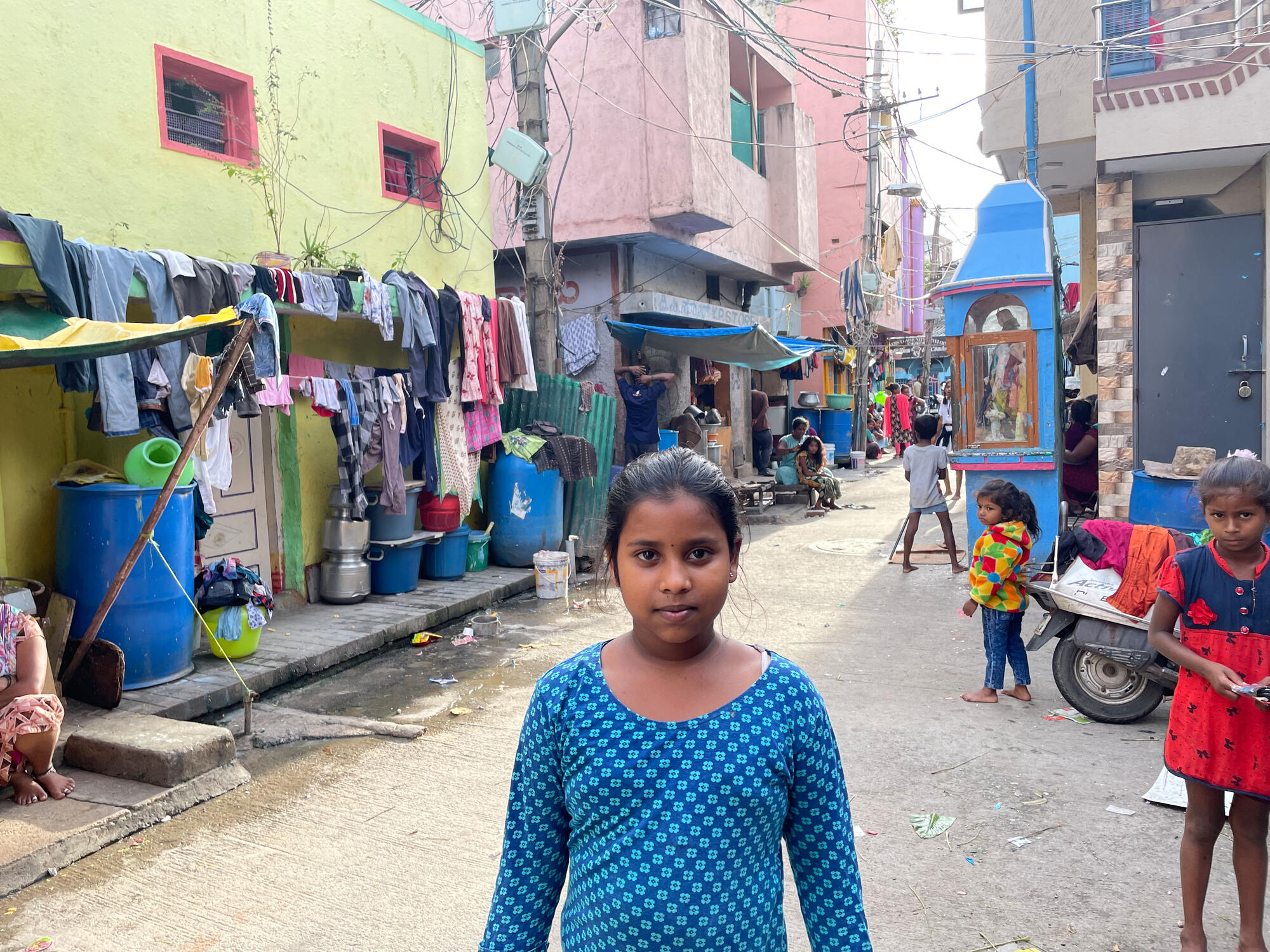 A young girl wearing blue, stands in the middle of a street in India