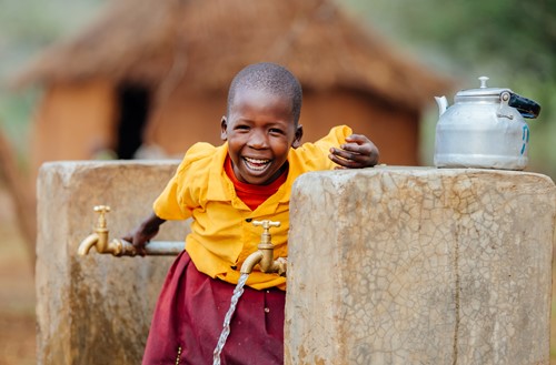 Girls smiling at a water tap