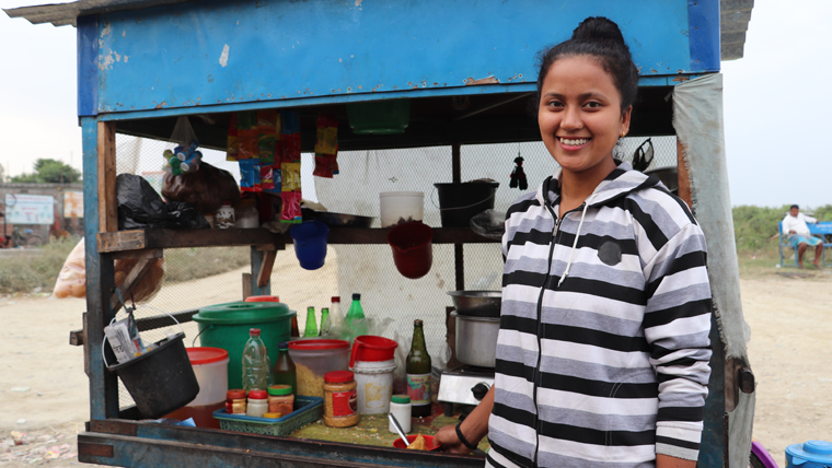 Saru stands in front of her parents' snack stand in Nepal