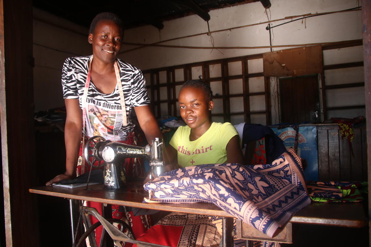 A young woman and her mother working together at a sewing machine