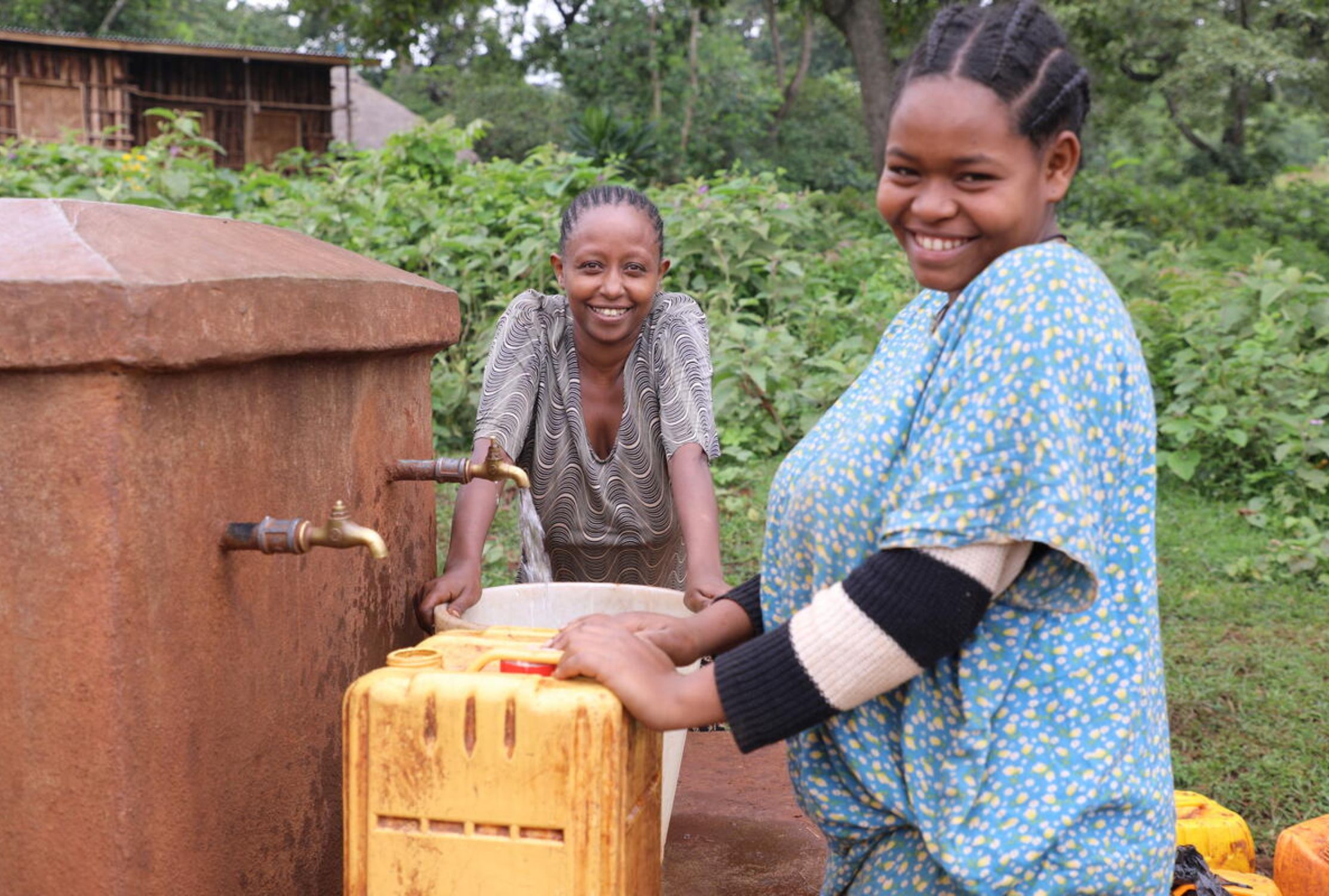 Ethiopian girls filling up their water bucket and smiling