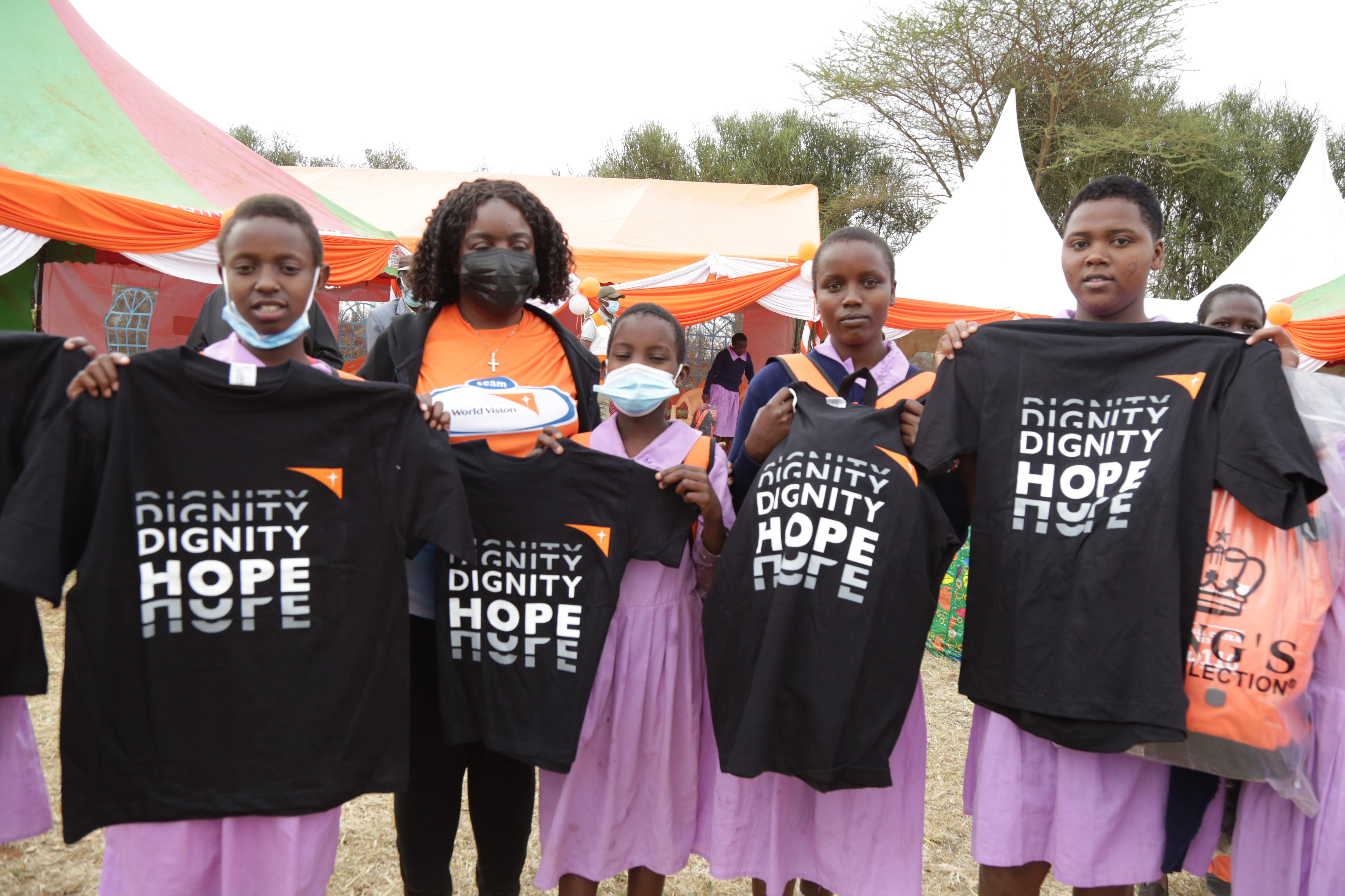 Girls in Kenya hold t-shirts bearing the slogan 'Dignity Hope'