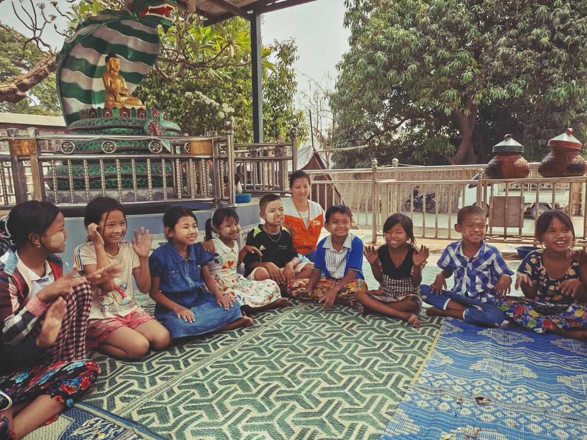 Staff member sits with a group of children in a child friendly space in Myanmar