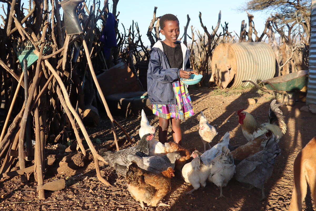 Minenhle, 9, feeds the chickens that have helped transform her life