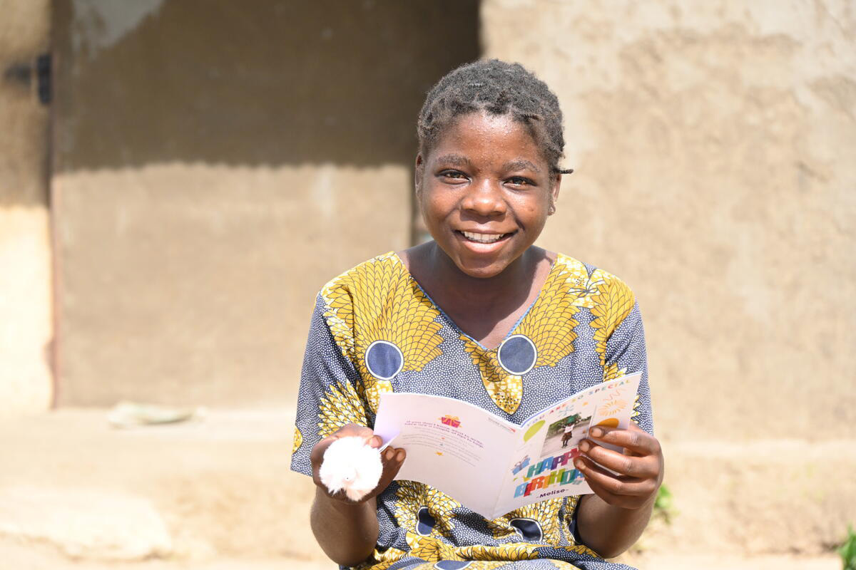 A child in Zambia holding a birthday card and smiling