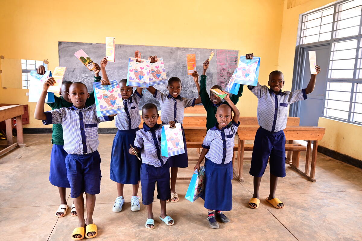 Group of Rwandan school children holding up their sponsorship gifts and letters