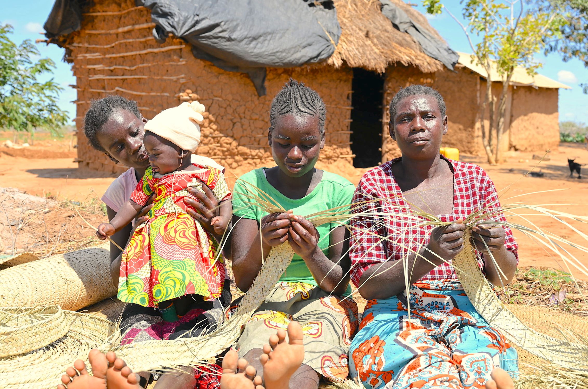 Kenyan family weaving outside their home during drought