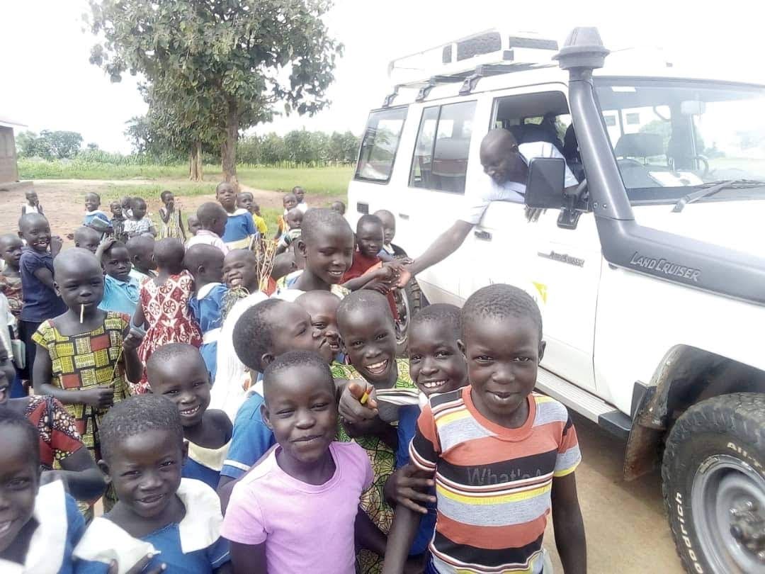 World Vision staff member greeting children from his vehicle, Uganda