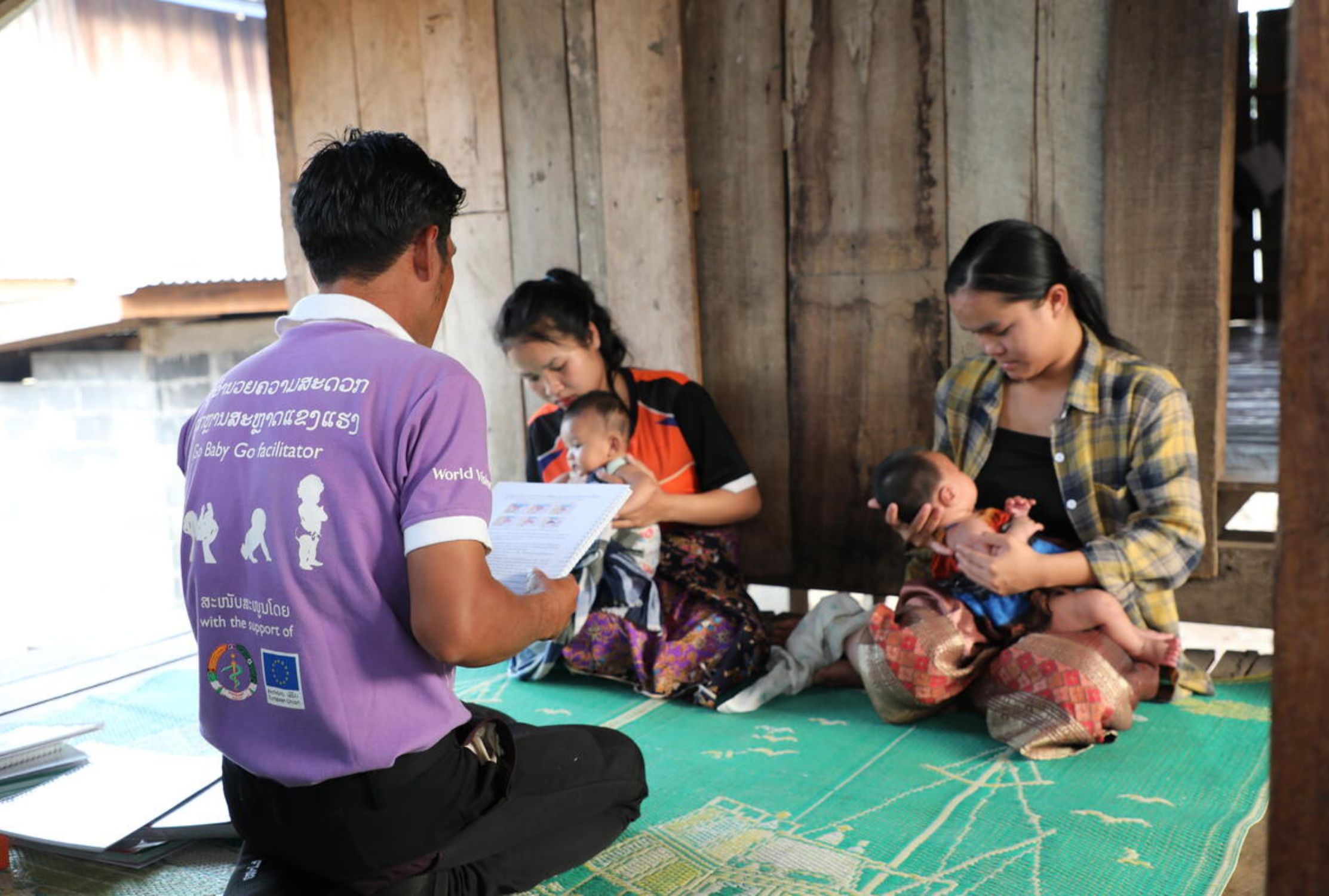Two girls holding their children, while a man helps them learn how to face the challenges of early parenthood