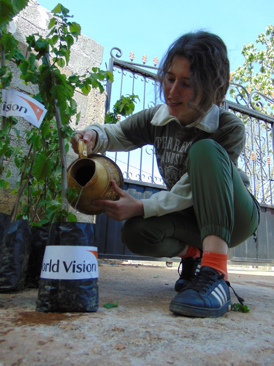 Teenage girl from Albania waters a hazelnut plant provided by World Vision to help her family during COVID-19