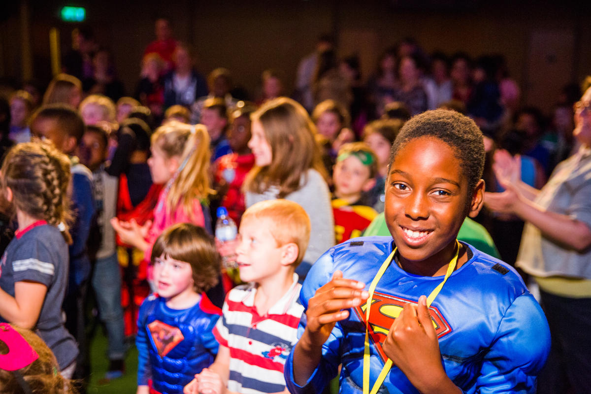 Children at Pumpkin Heroes Halloween party dressed as superheroes, playing and having fun.