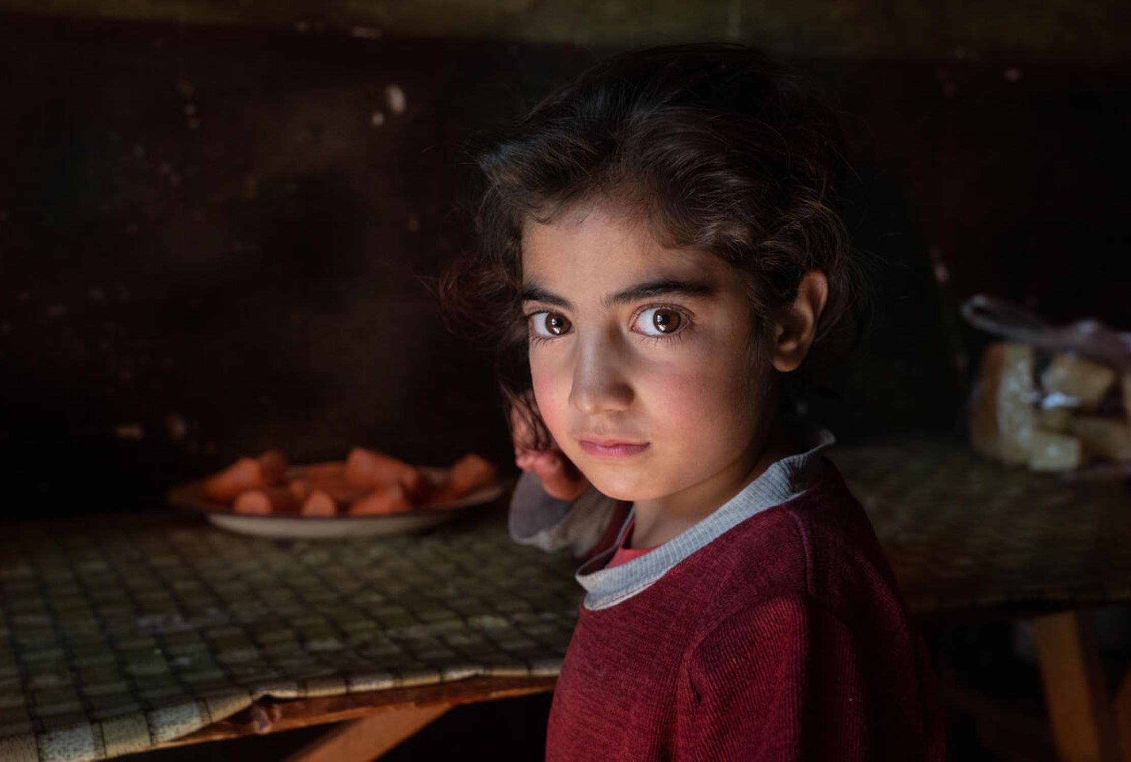 Young girl from Armenia looking at the camera from a dark room
