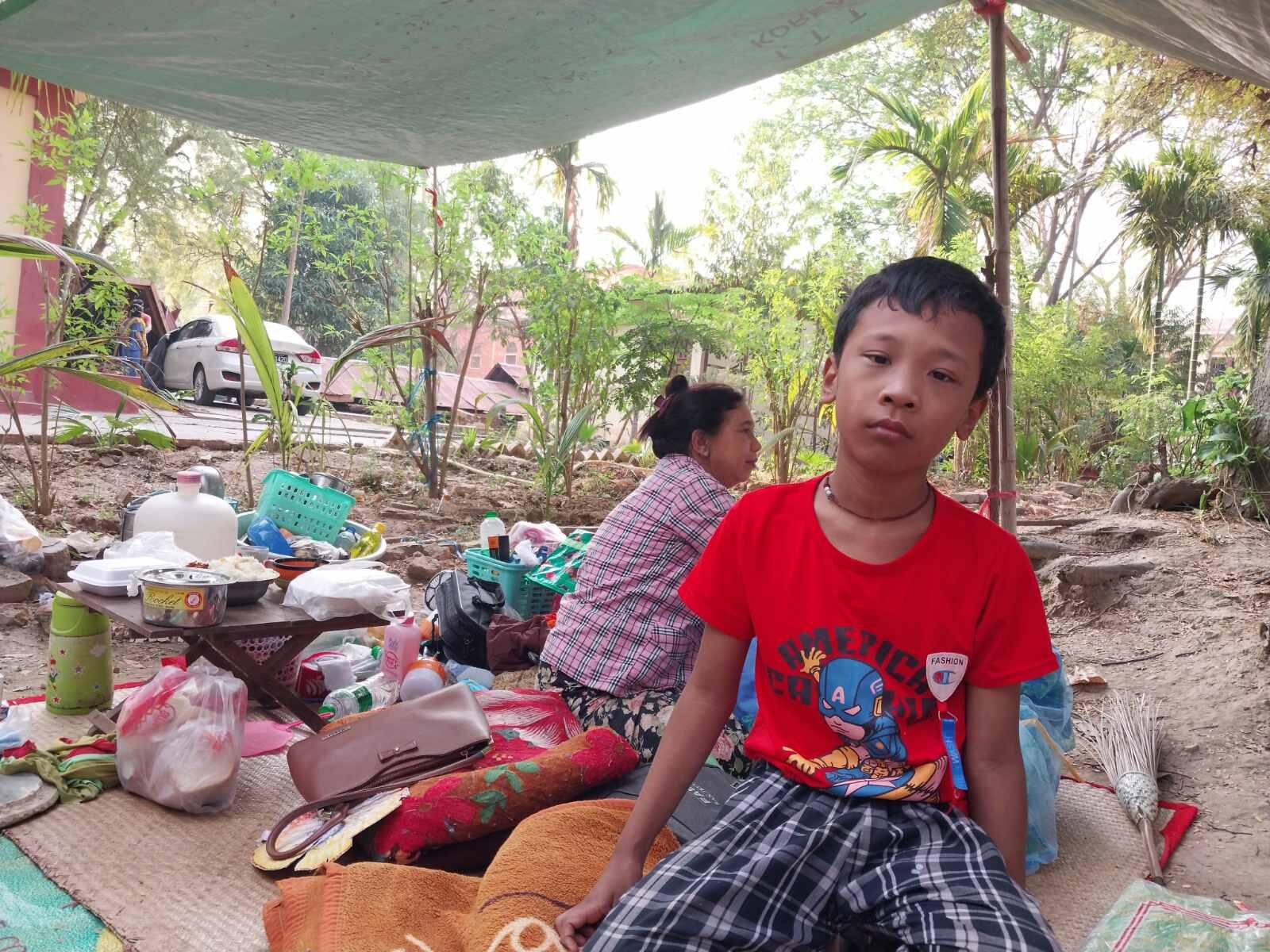 A child in Myanmar sits under a tarpaulin following the devastating earthquake