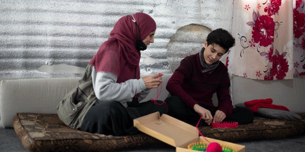 Syrian teenage refugee with his mum, learning to knit