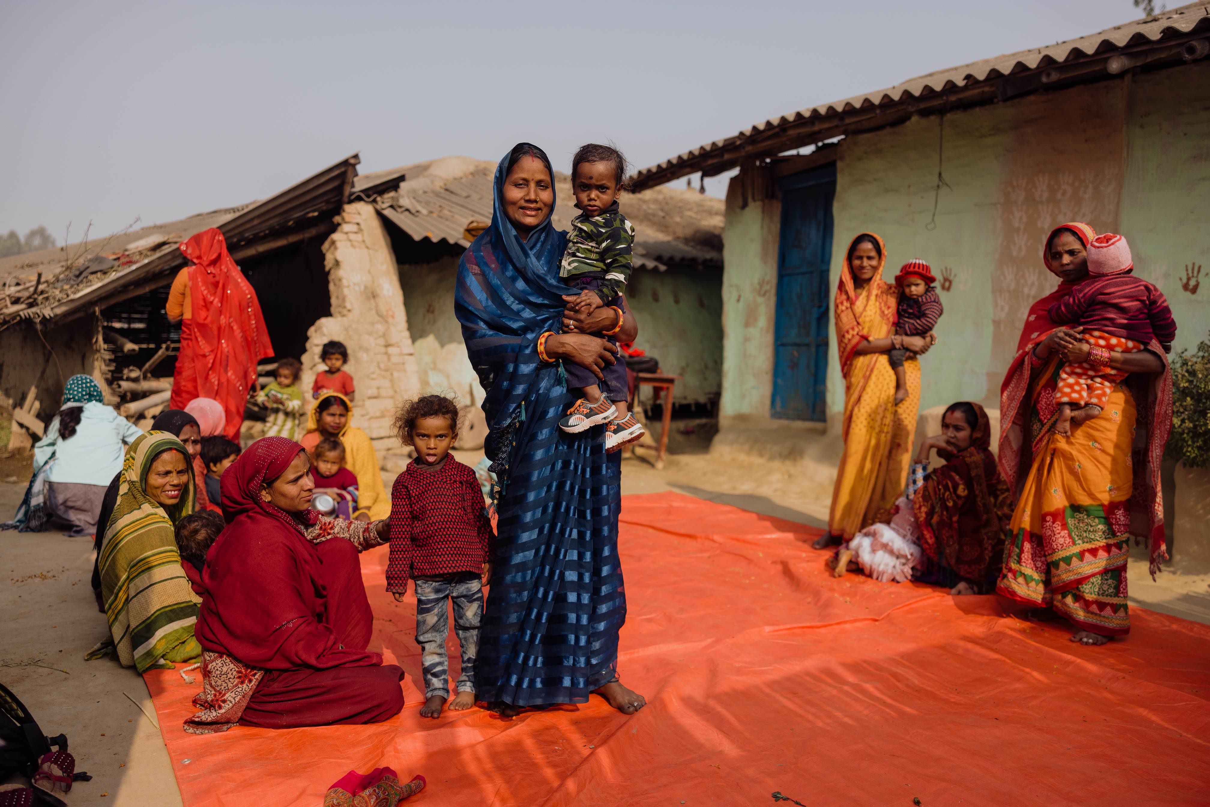 Woman from Nepal holding her young child, surrounded by others that are part of the nutrition programme