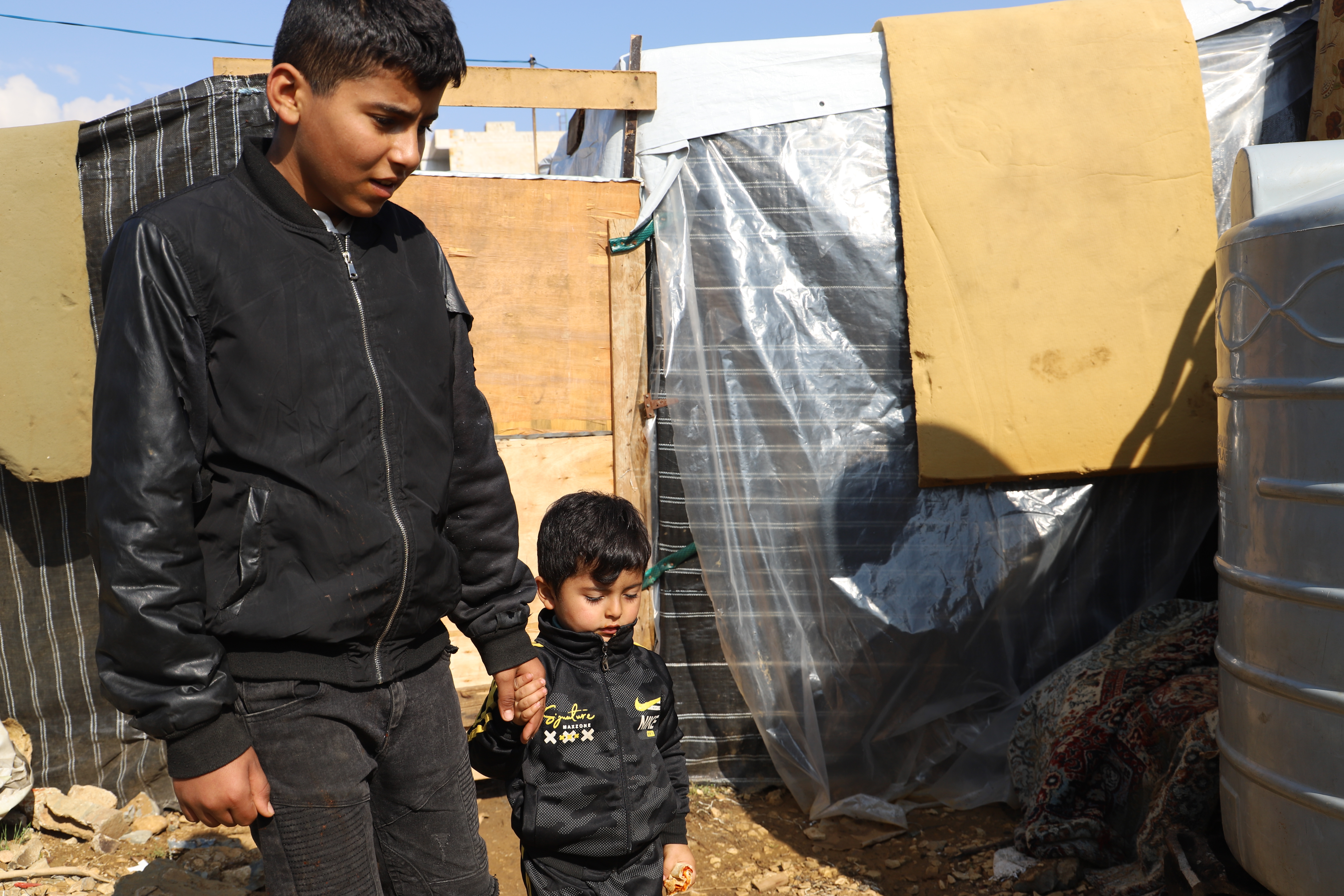 Boy from Syria pictured walking with his younger brother, holding hands