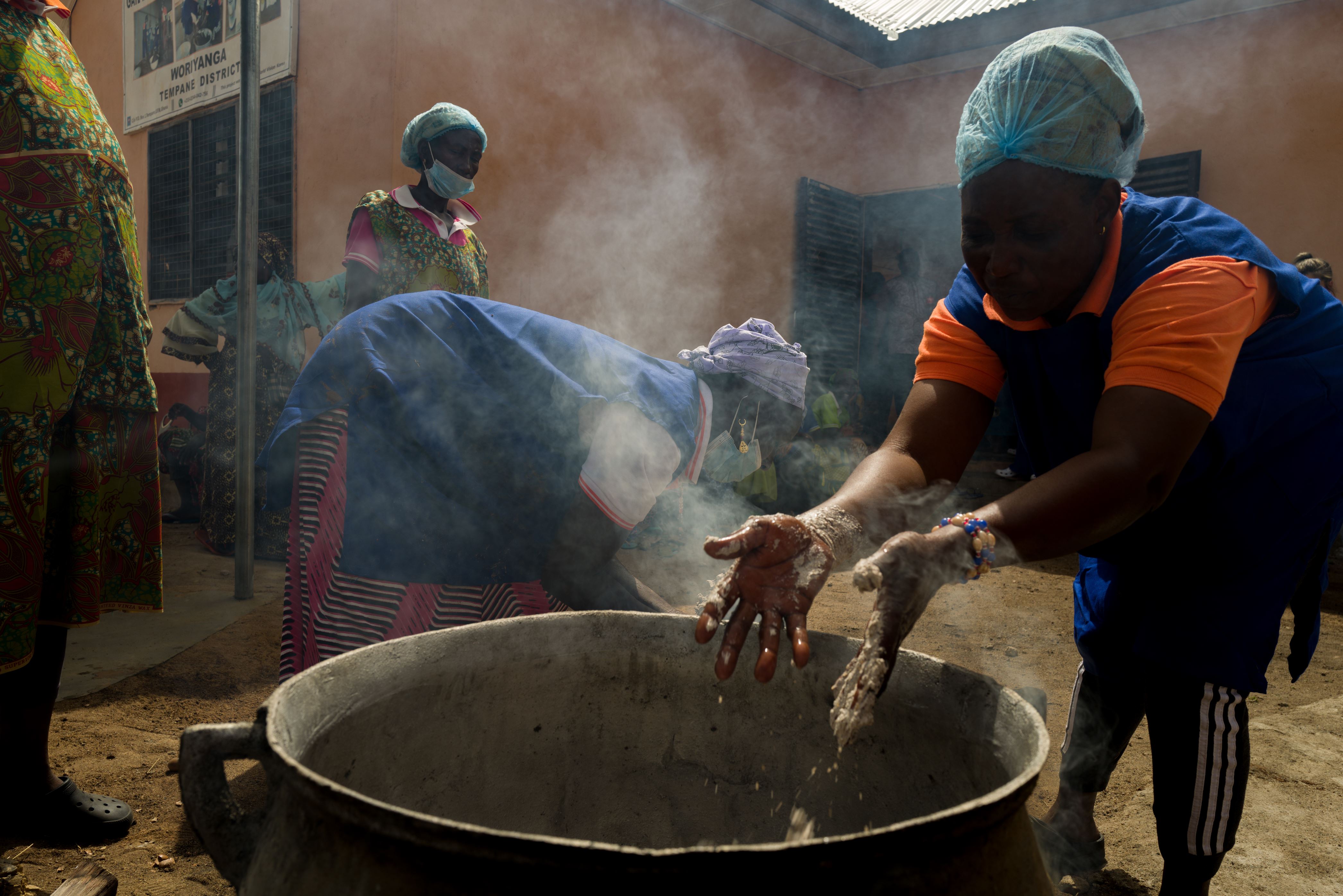 A classroom full of students wave at the camera with smiles on their faces