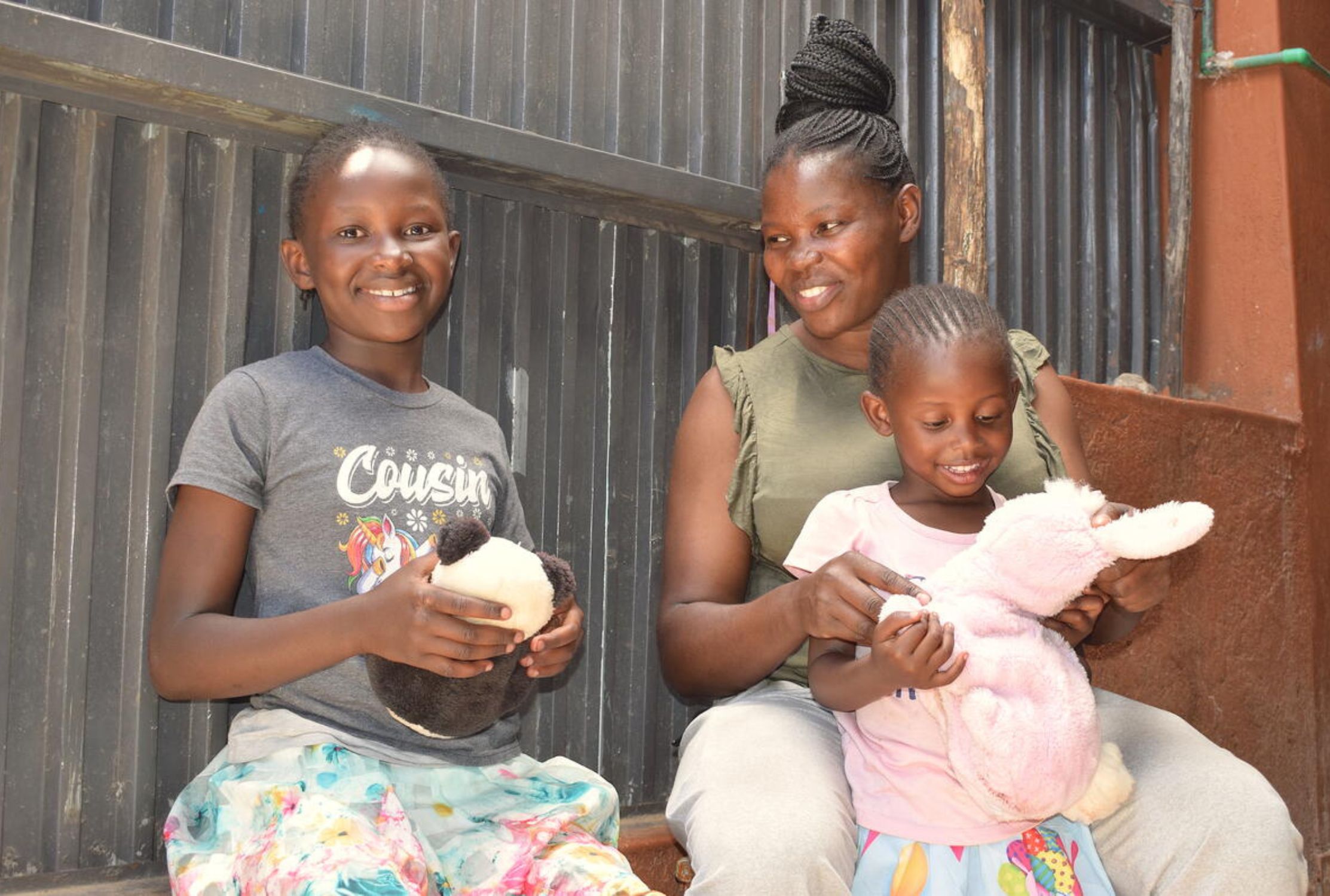 Kenyan mother sat with her two daughters, all smiling