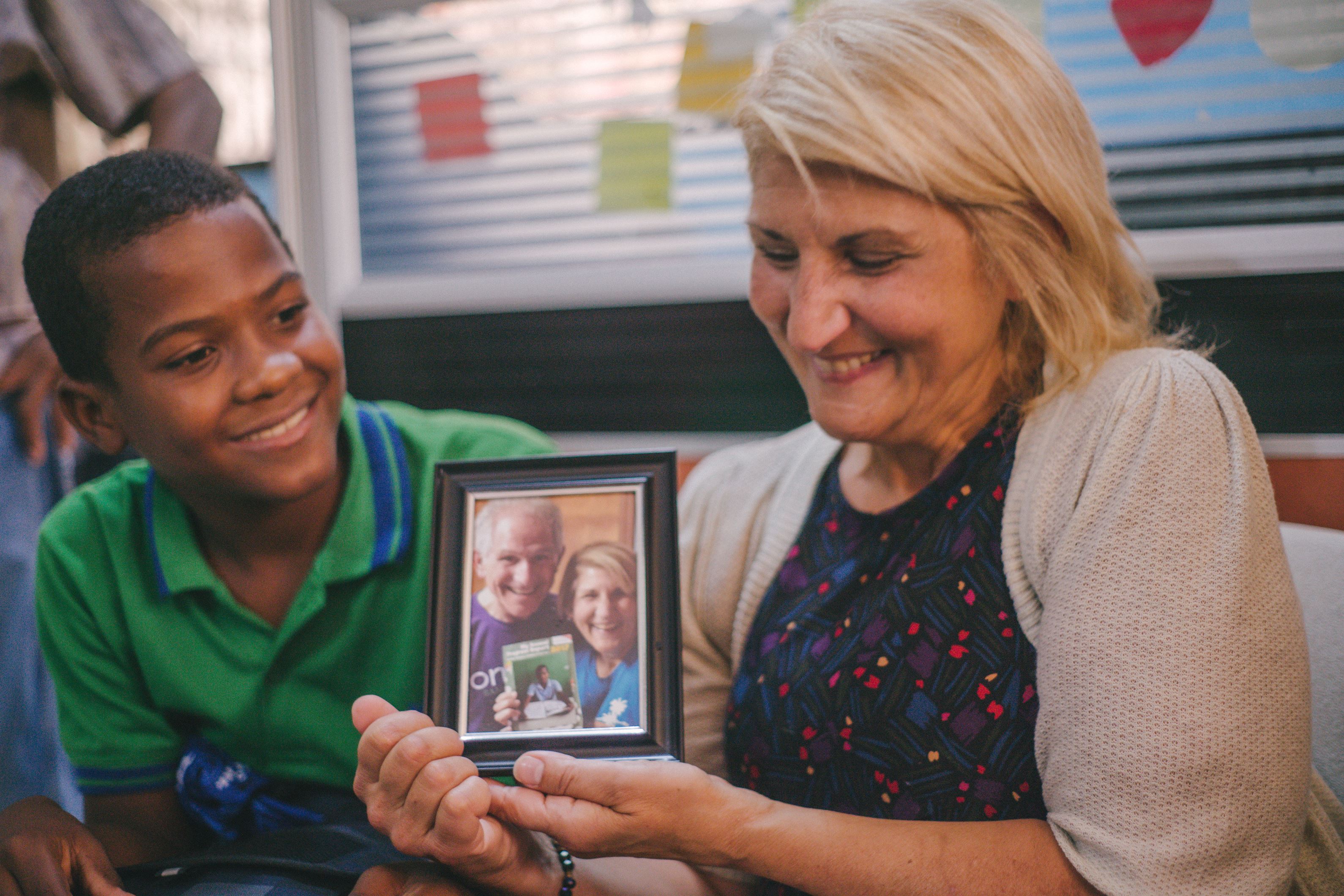 Child and an adult smile as they look at a photo together in the Dominican Republic