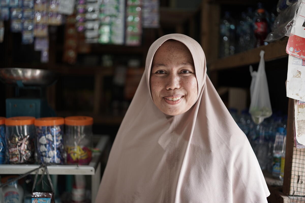 Business owner Khairani smiles while standing in her store.