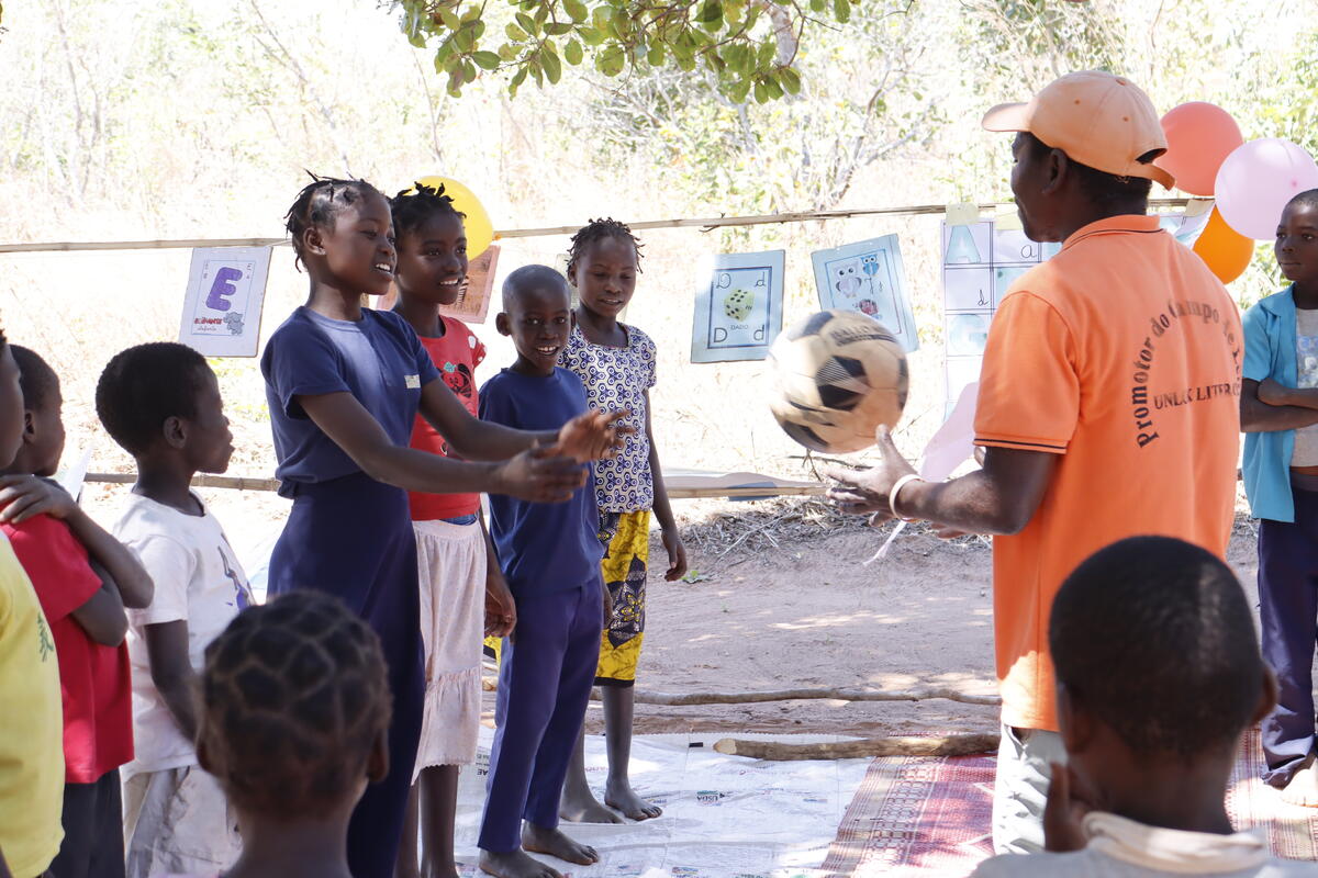 A reading camp promoter helping children with their reading.