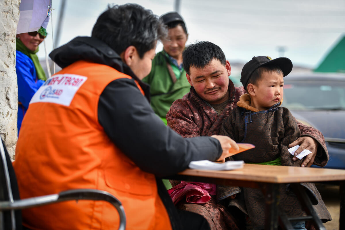 Man and child sat at a table with World Vision staff