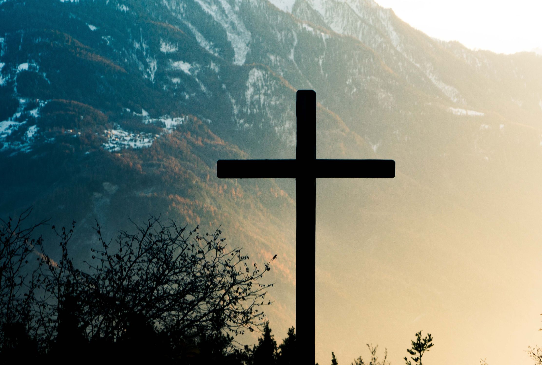 Silhouette of a cross in front of scenic mountains