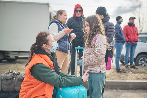 A World Vision worker greets a girl crossing the boarder from Ukraine