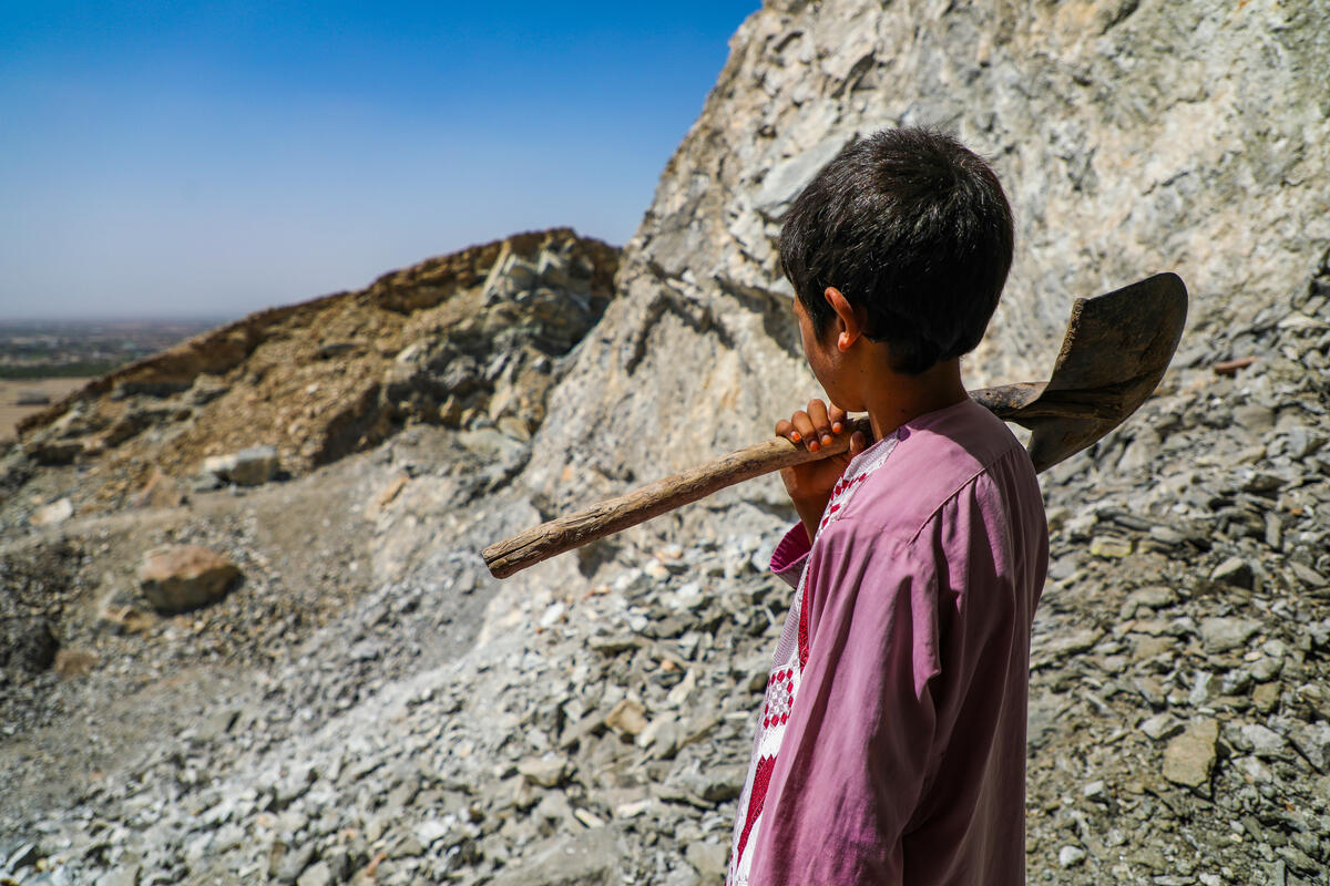 Child on mountain holding shovel.