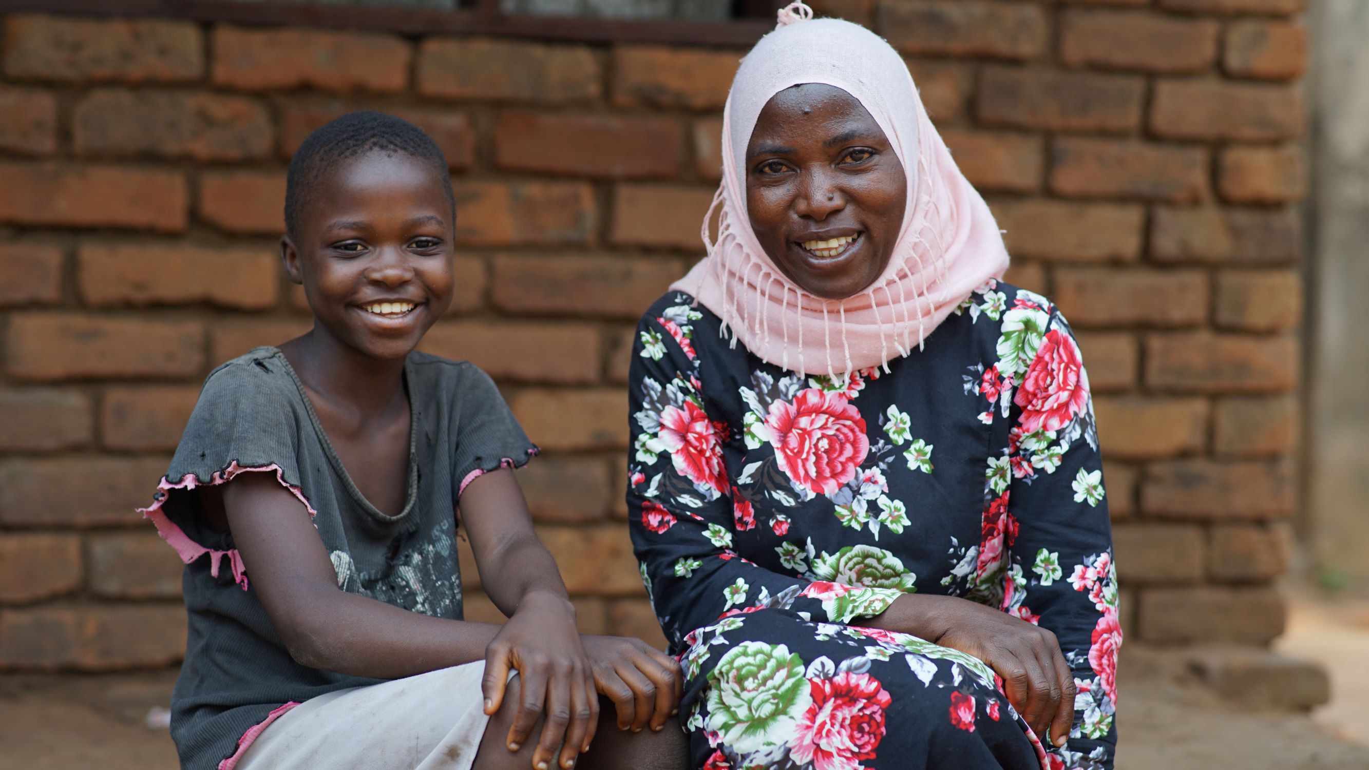 In Malawi, a mother and daughter sit together, smiling