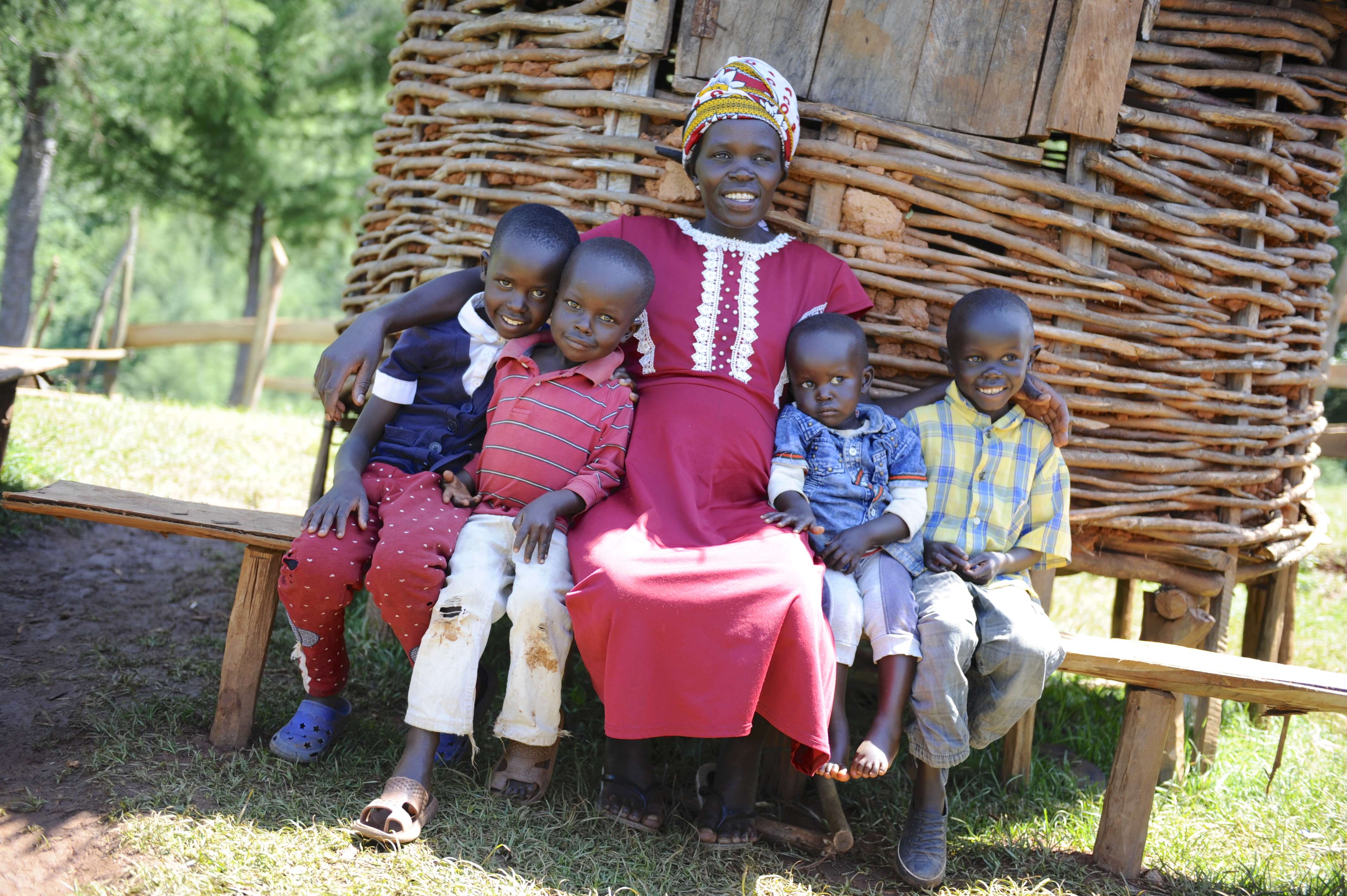 Pregnant mother and her 4 children sitting outside their house