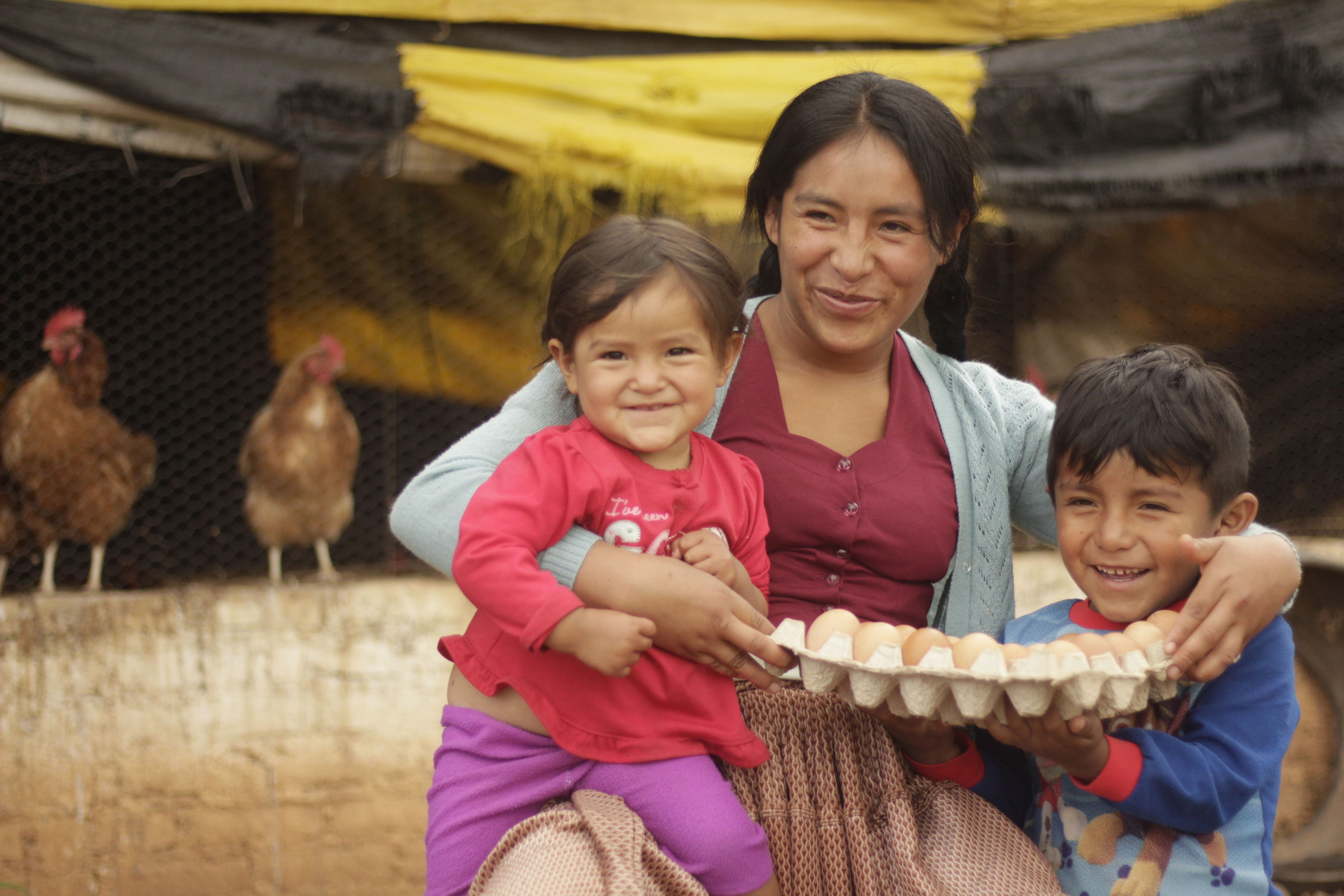 A mother and her two small children, in Bolivia, hold the nutritious eggs their chickens have laid for them.