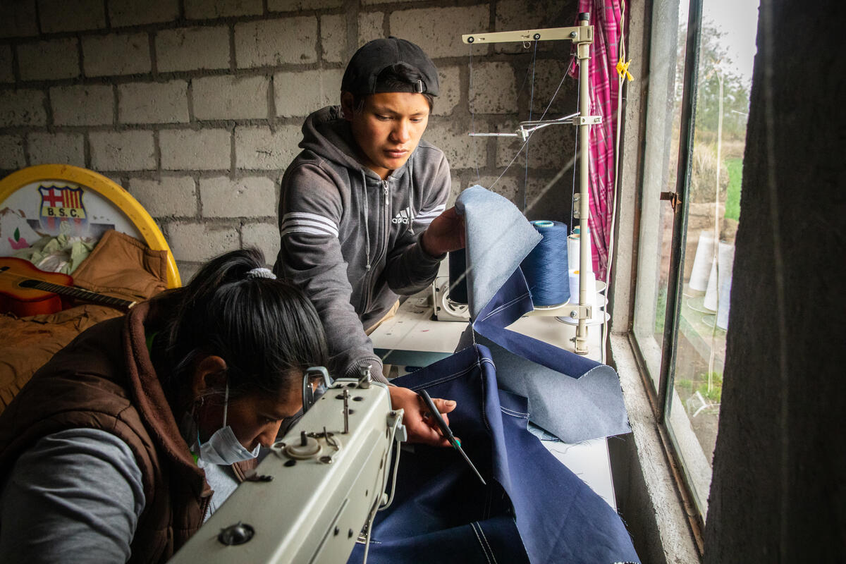 Teenage boy helps his mum at her sewing machine