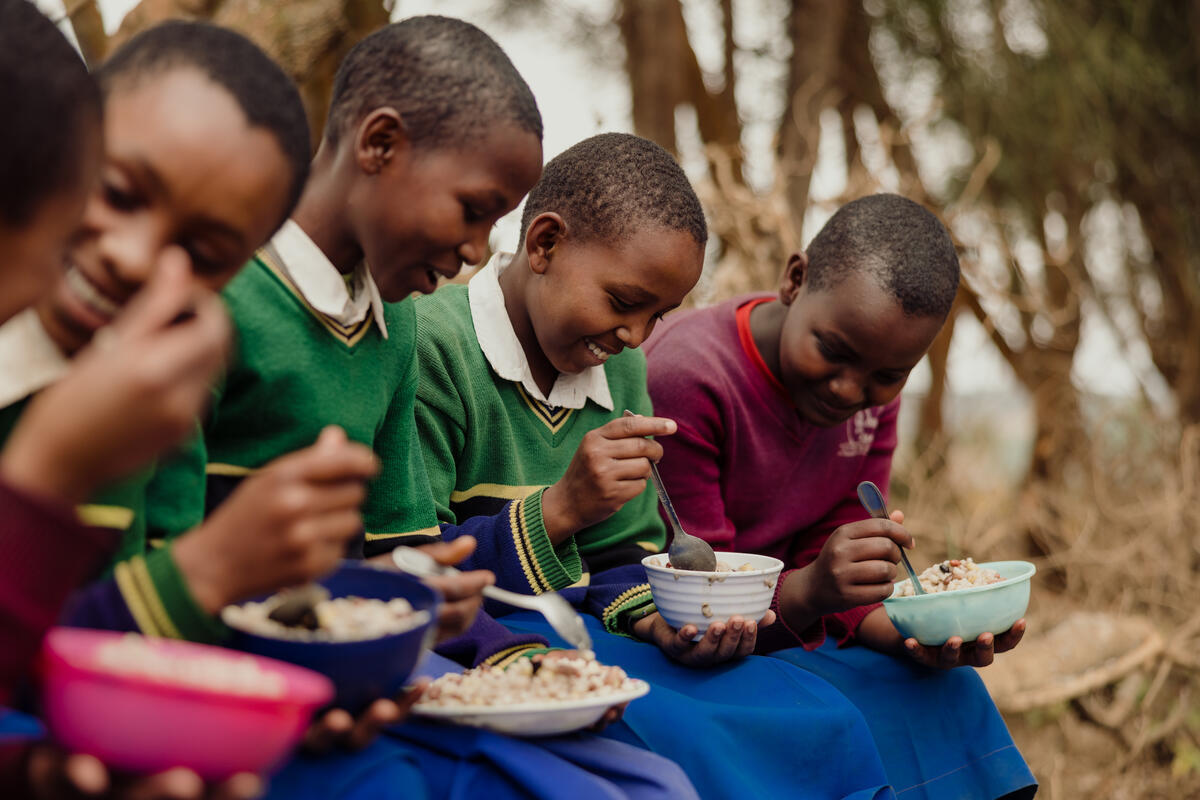 A group of young school girls sit with their bowls of food