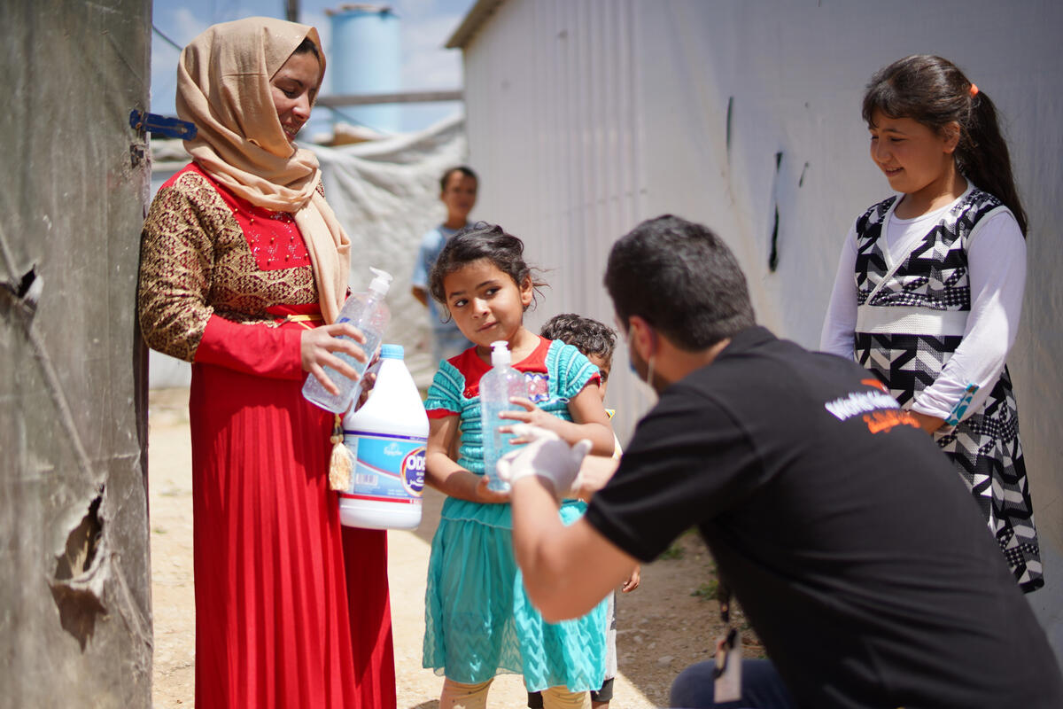 World Vision worker hands out supplies to children and a woman in a refugee camp in Lebanon