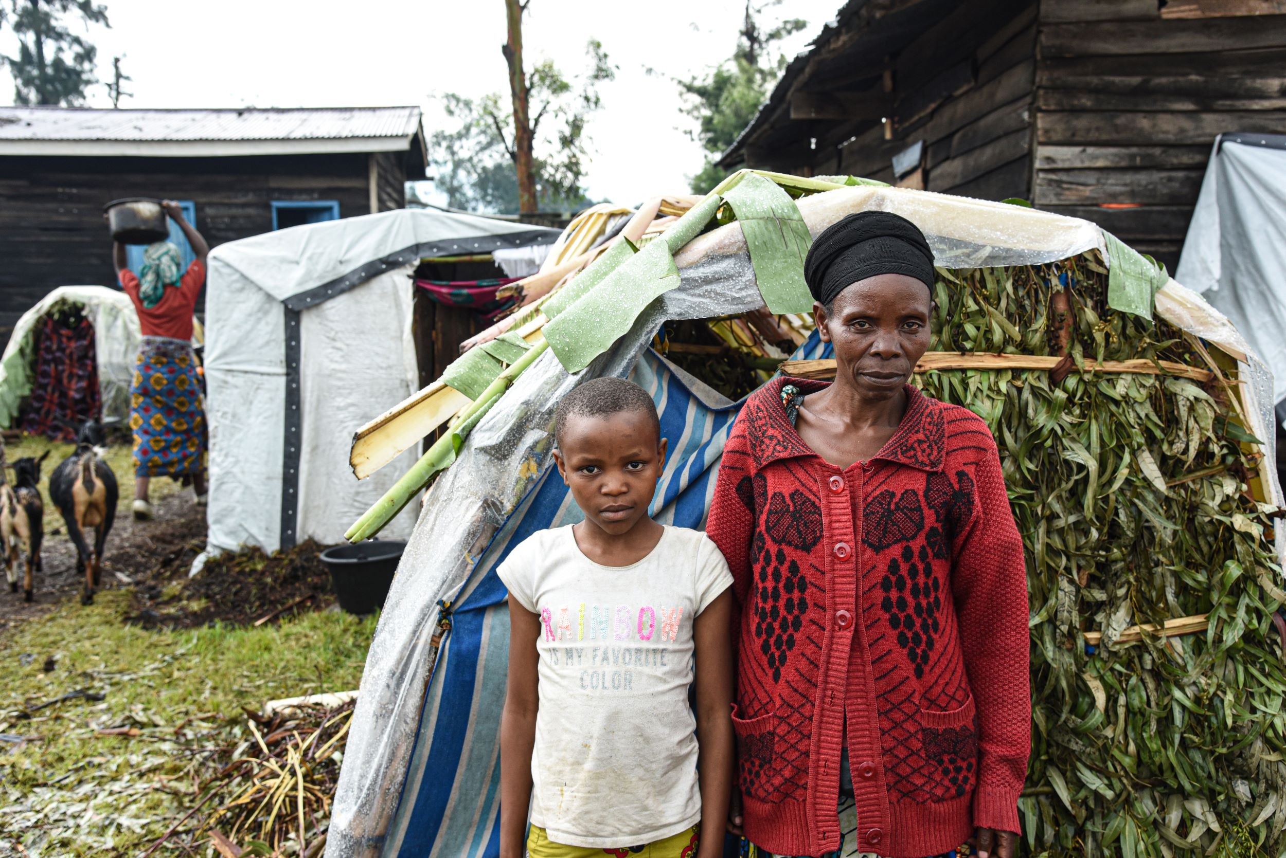 Congolese mother standing with her daughter in front of the shelter they now call home