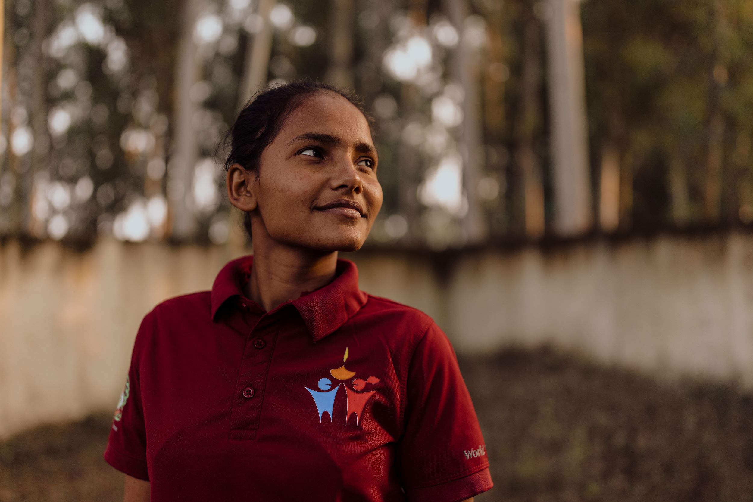 Smiling teen Nepalese girl in deep red polo shirt