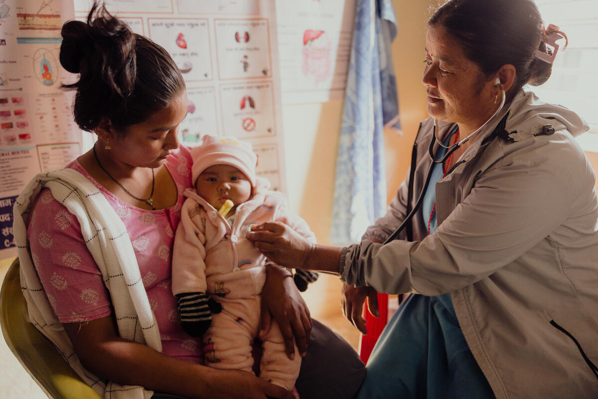 A mother and baby in Nepal receiving medical support and nutritional care from a healthcare workers.