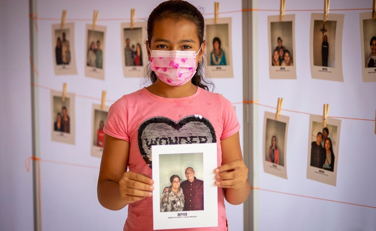 Guatemalan girl wearing a mask and holding up a picture of her child sponsors