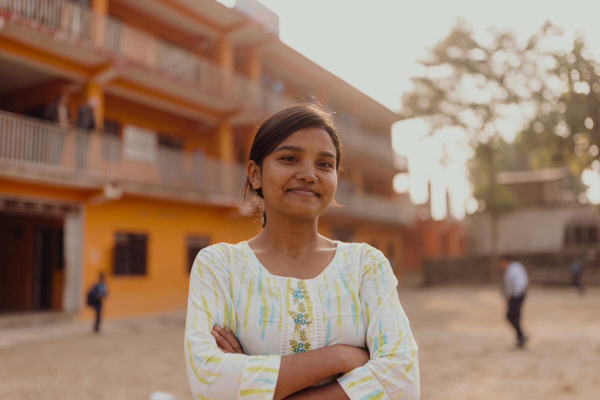 Nepali girl in cream dress smiling with arms crossed