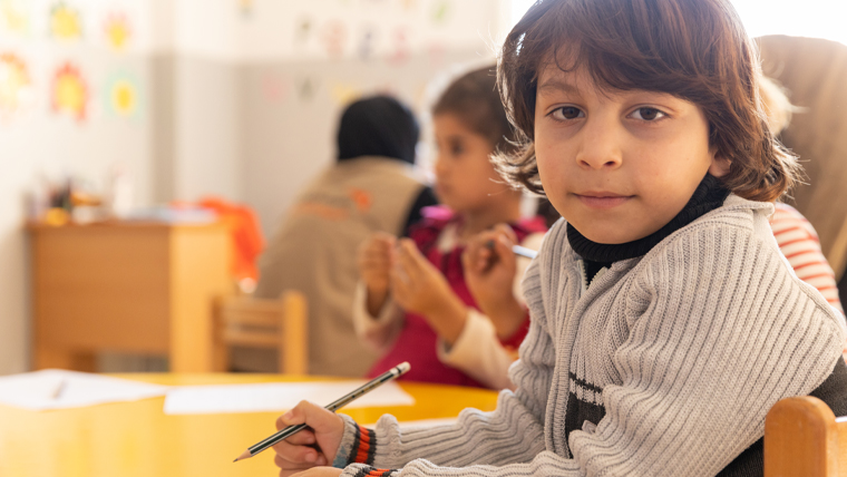 Five-year-old Mouataz, originally from Syria, draws at a table alongside other children