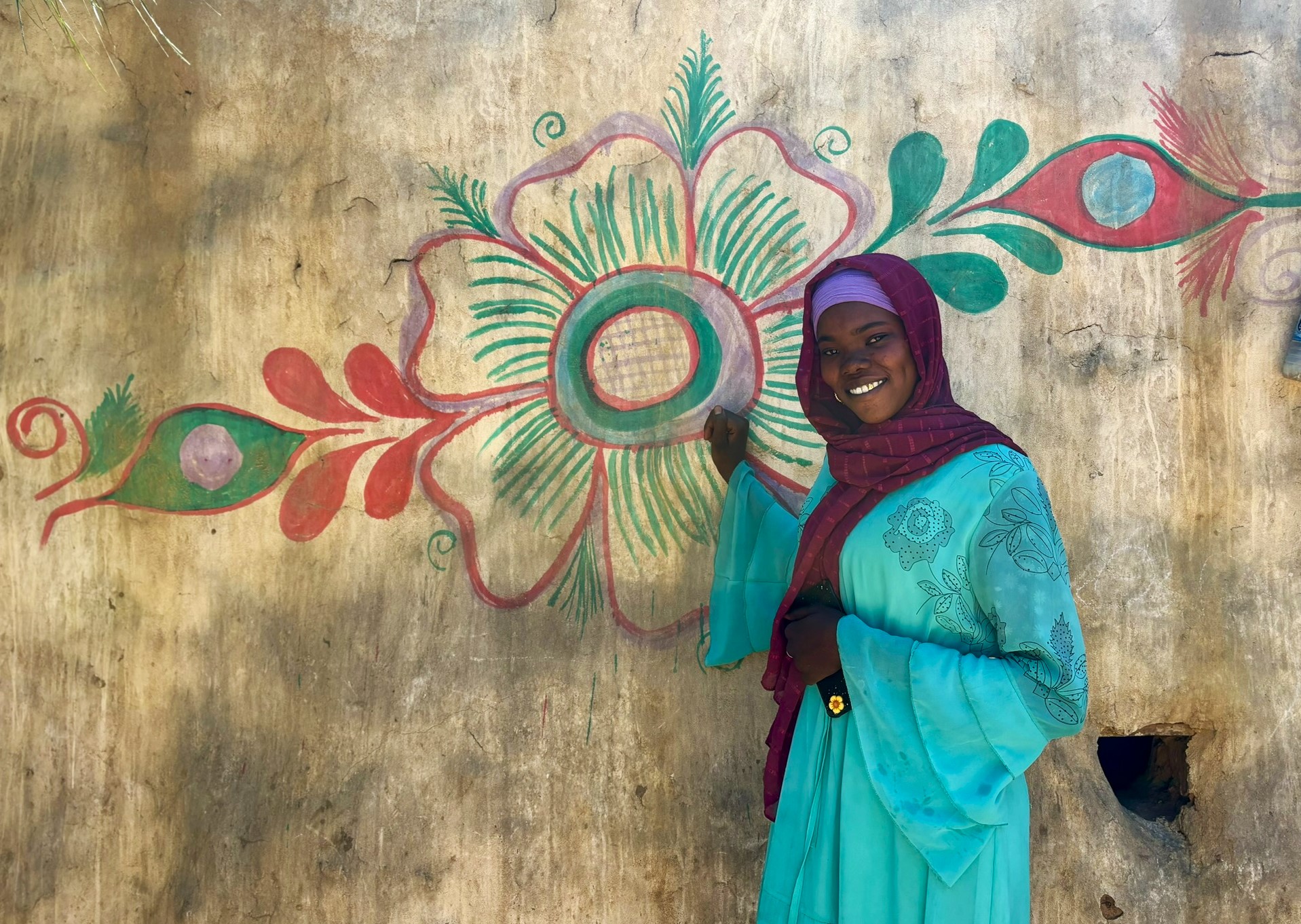 Salha in front of one of the beautiful flowers she has painted across the exterior walls of her family’s home