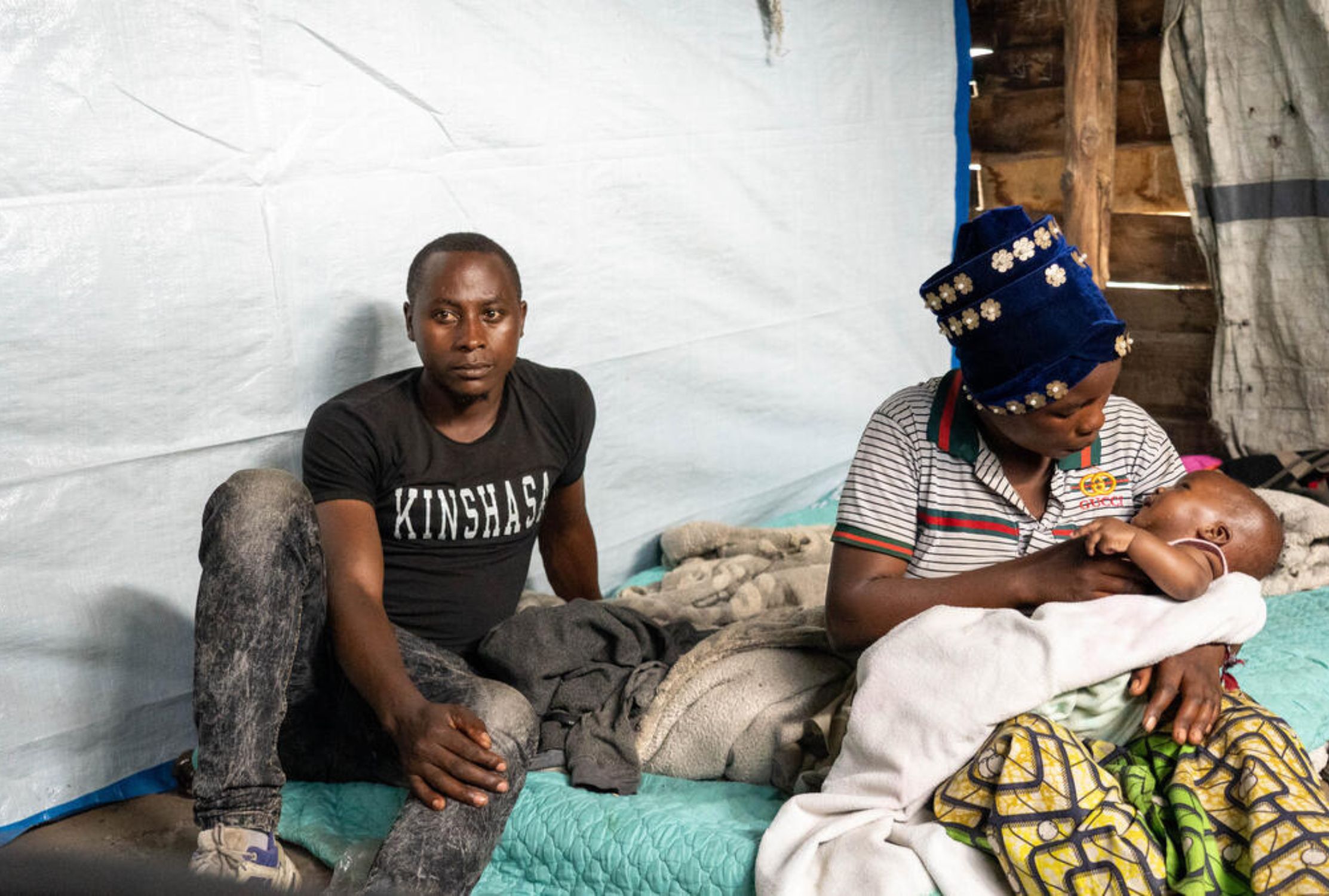 Mother and father from the DRC sat on the floor of their temporary home, the mother is holding their three-month-old daughter
