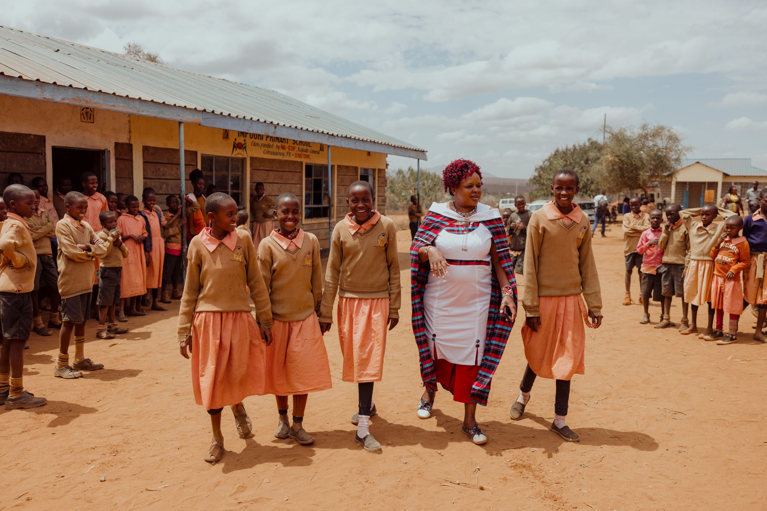 Kenyan woman and girls in school uniform walking together outside