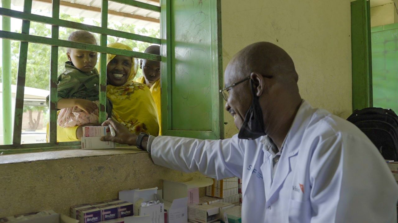 Sudan medic welcoming mother and child to mobile clinic