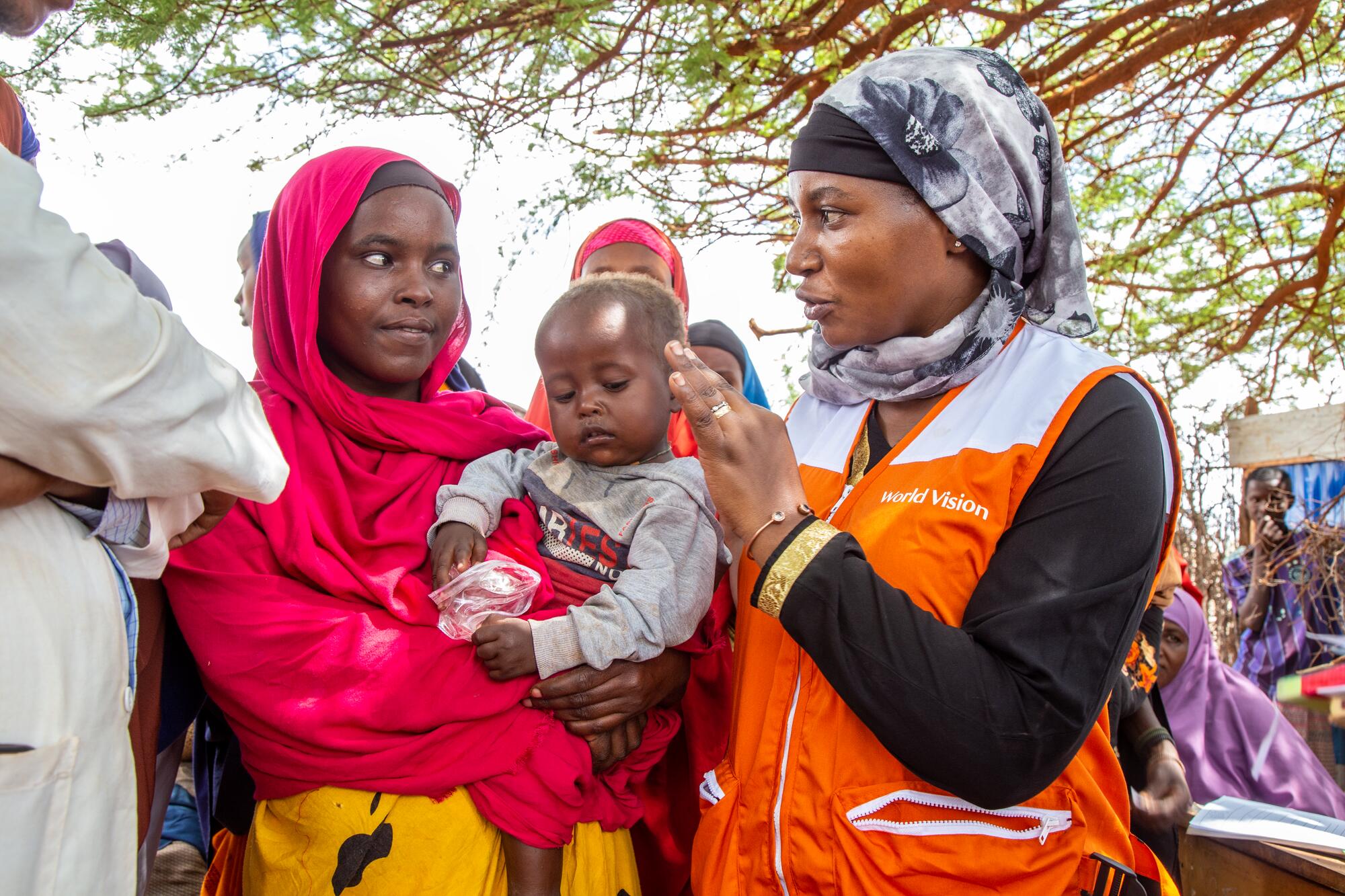 Somali mother and her baby speaking to World Vision staff