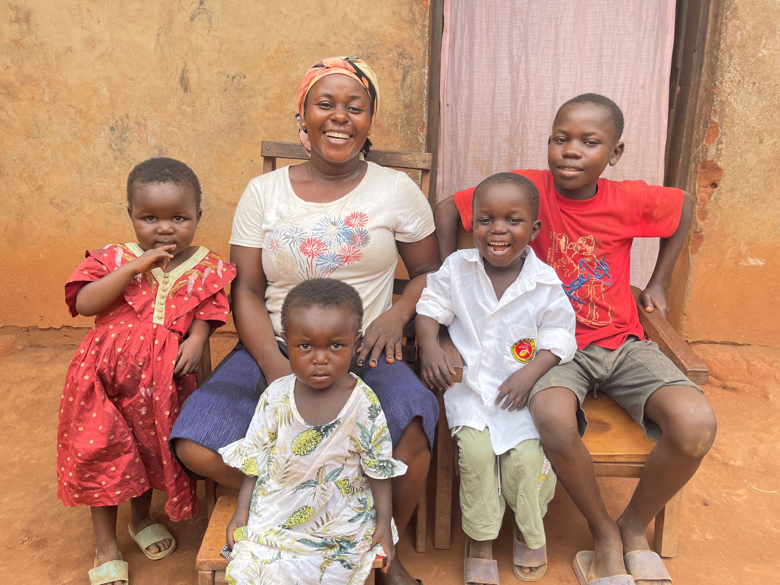 A mother poses outside her home with her four happy, healthy children 