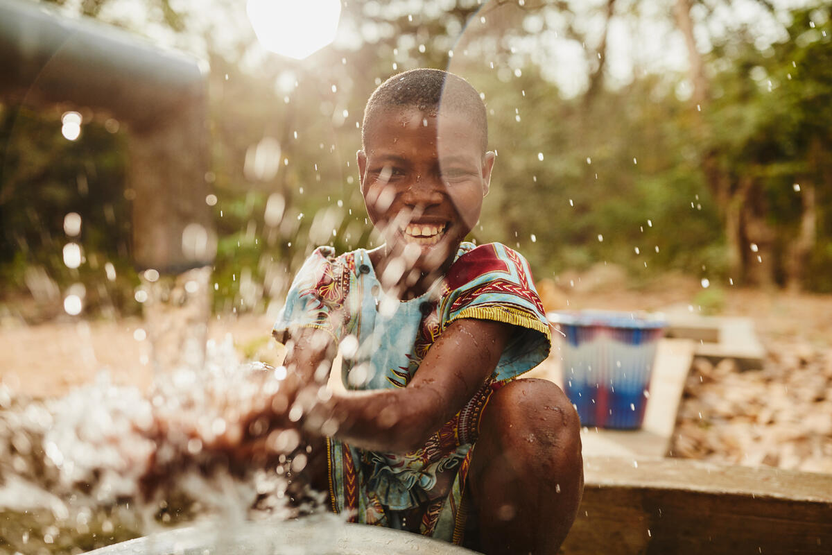 A child smiles and splashes in clean drinking water