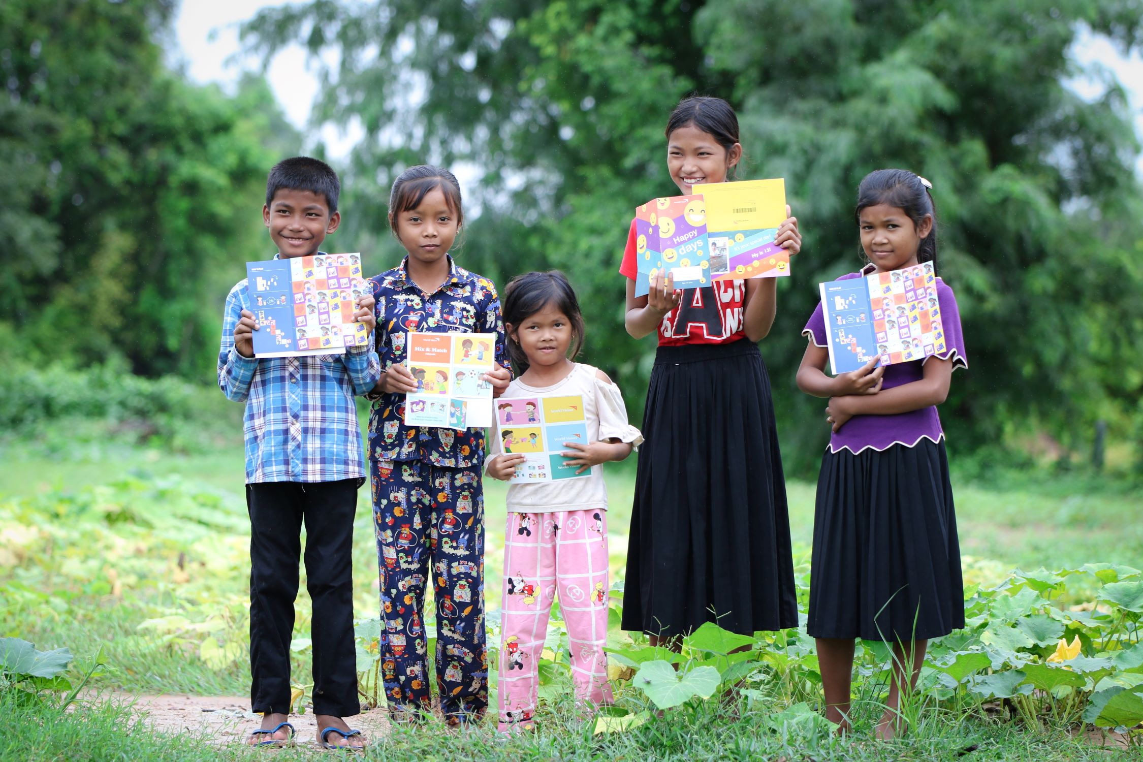 five children from Cambodia holding up birthday cards from their child sponsors