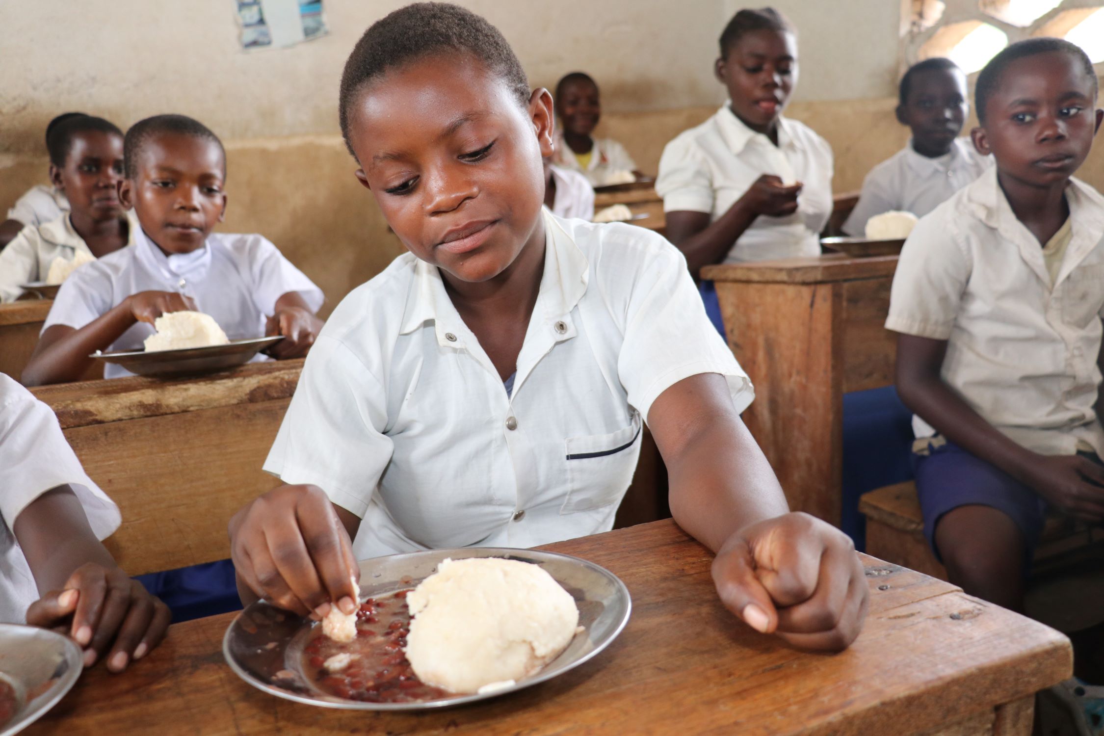 Girl and her class having school meals in DRC